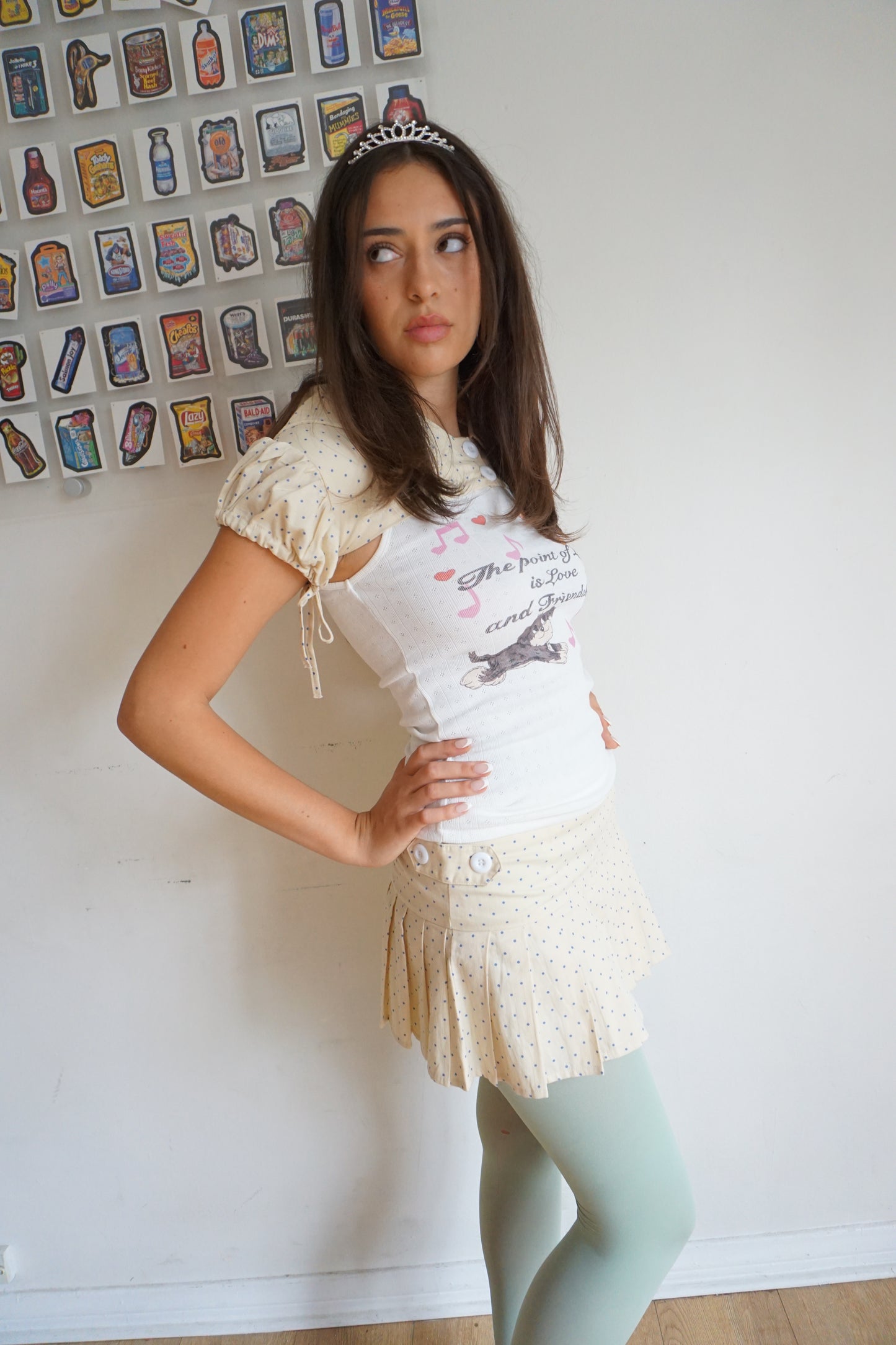 Girl wearing a cream pleated skirt with blue polka dots and a tiara and blue tights