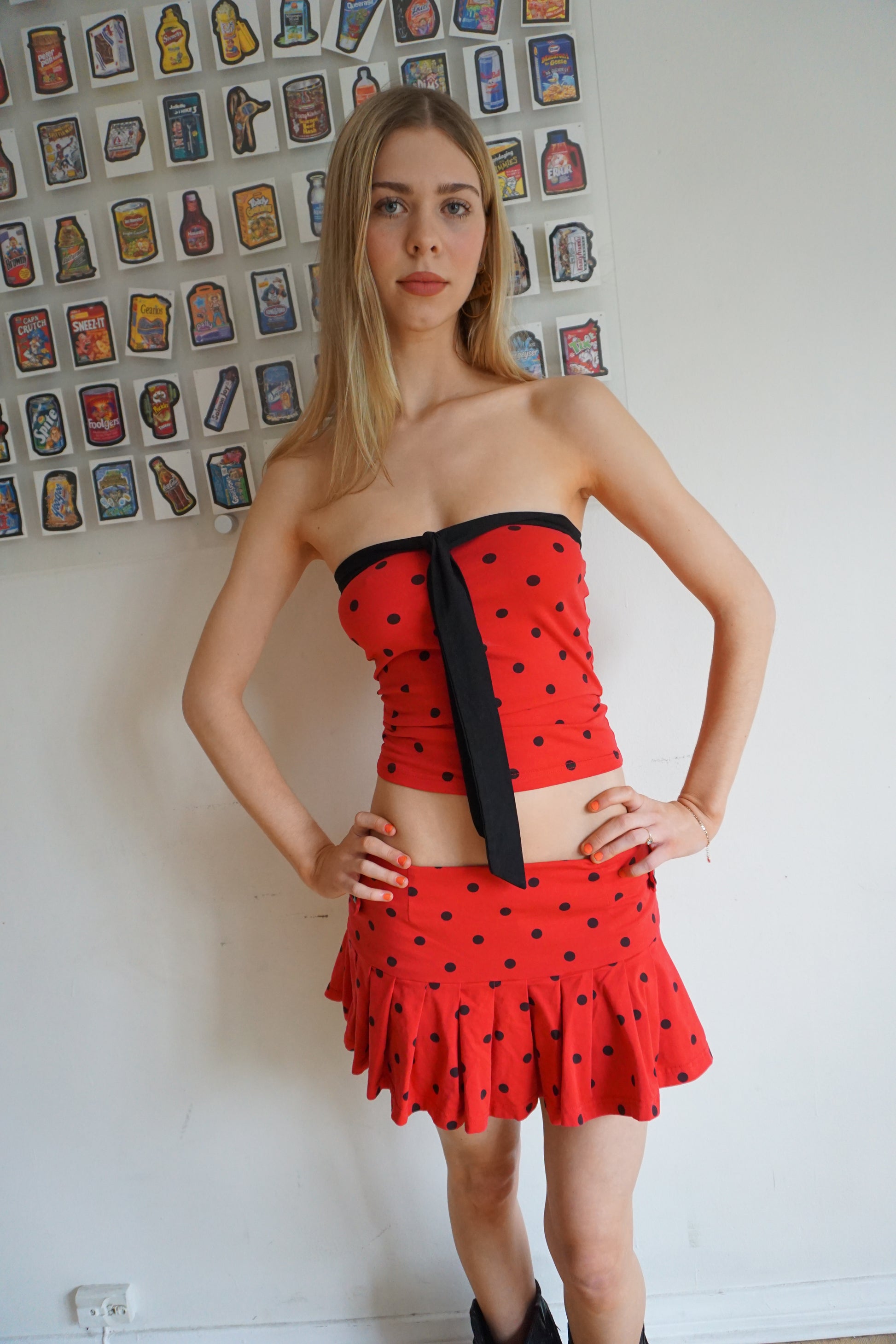 Girl wearing red tube top with black polka dots and black tie and matching skirt