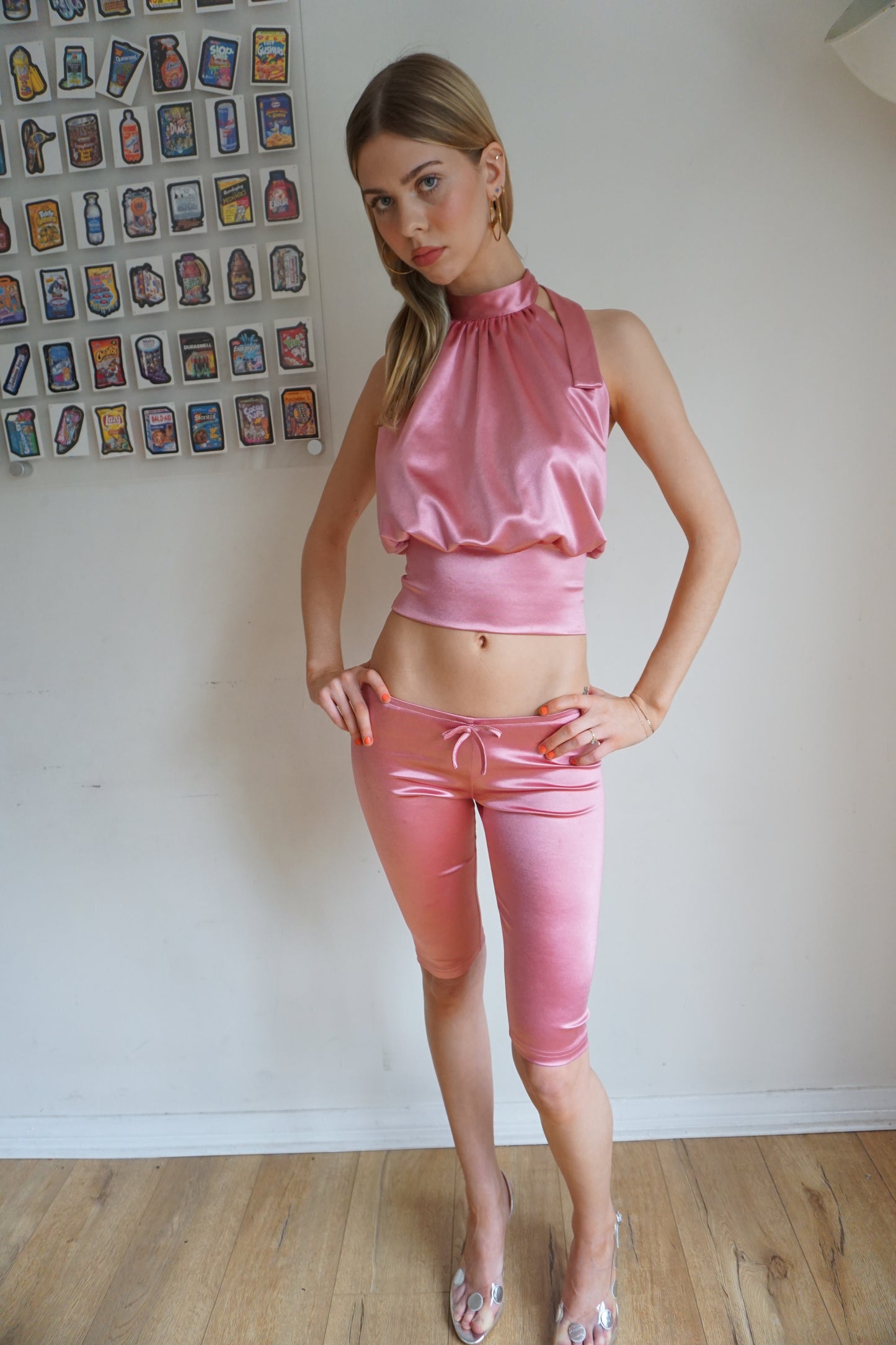 Girl wearing blush pink satin halter top with open back and matching capris