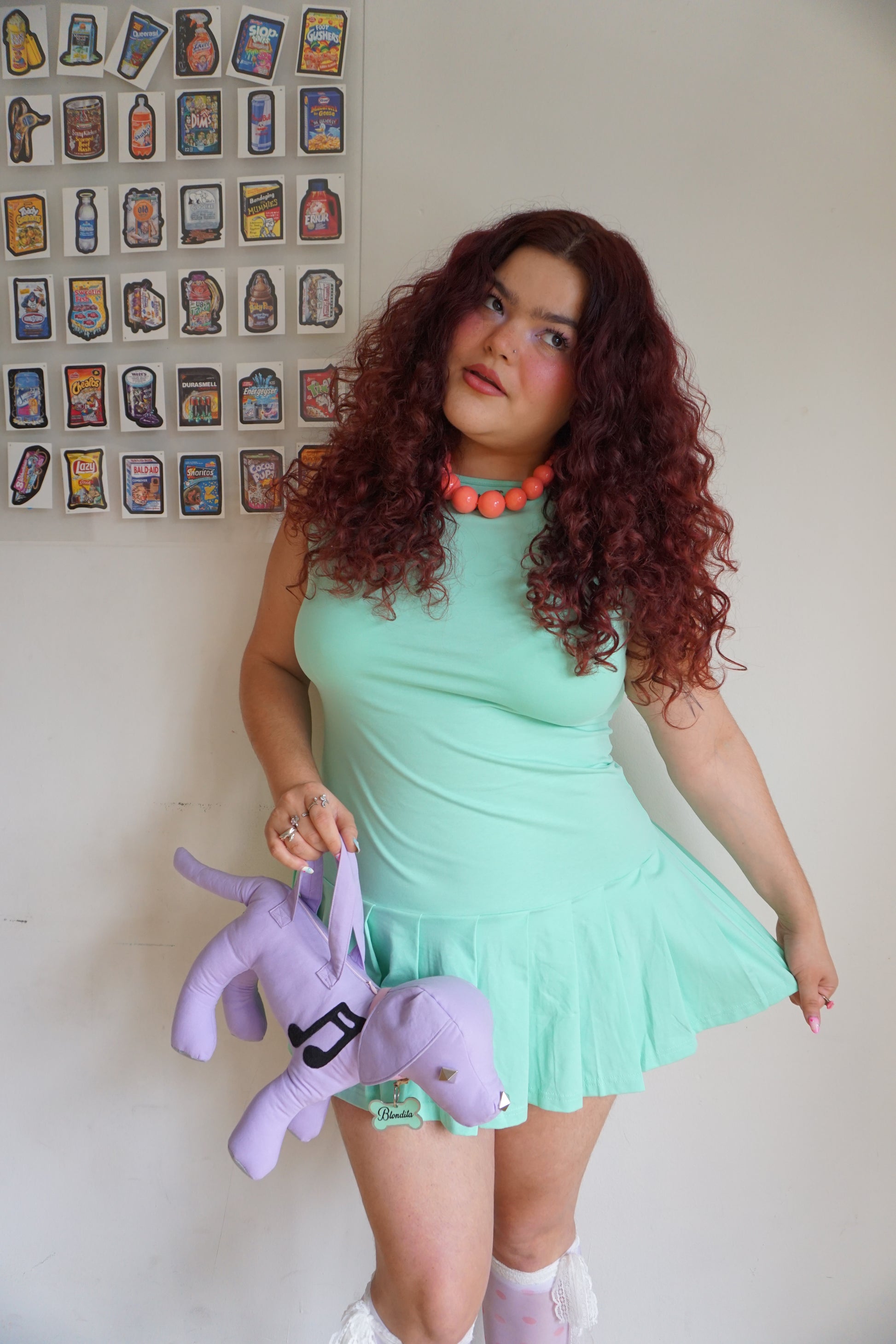 girl wearing a mint green drop waist pleated dress with a dog purse
