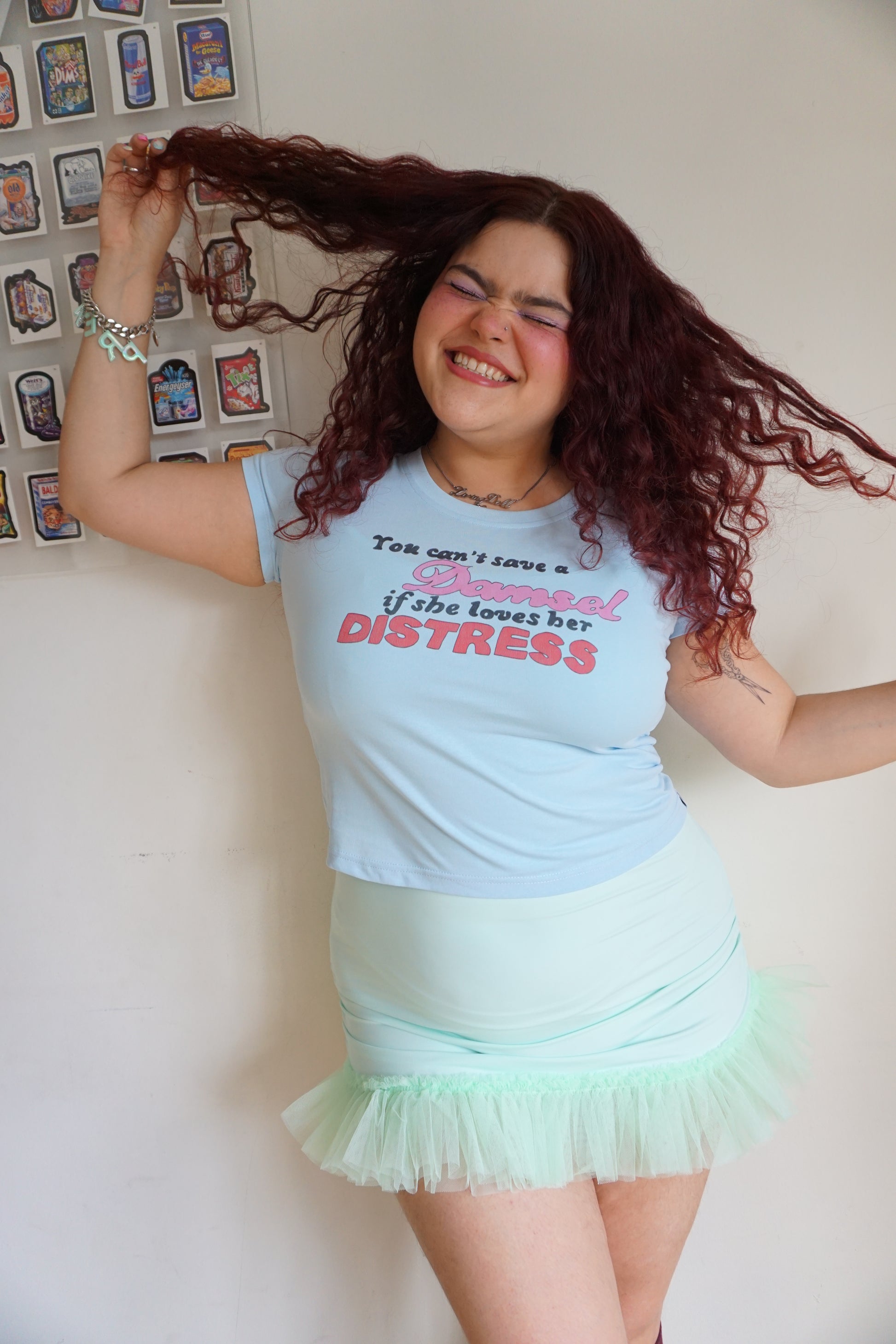 woman wearing blue baby t shirt that says you can’t save a damsel if she loves her distress