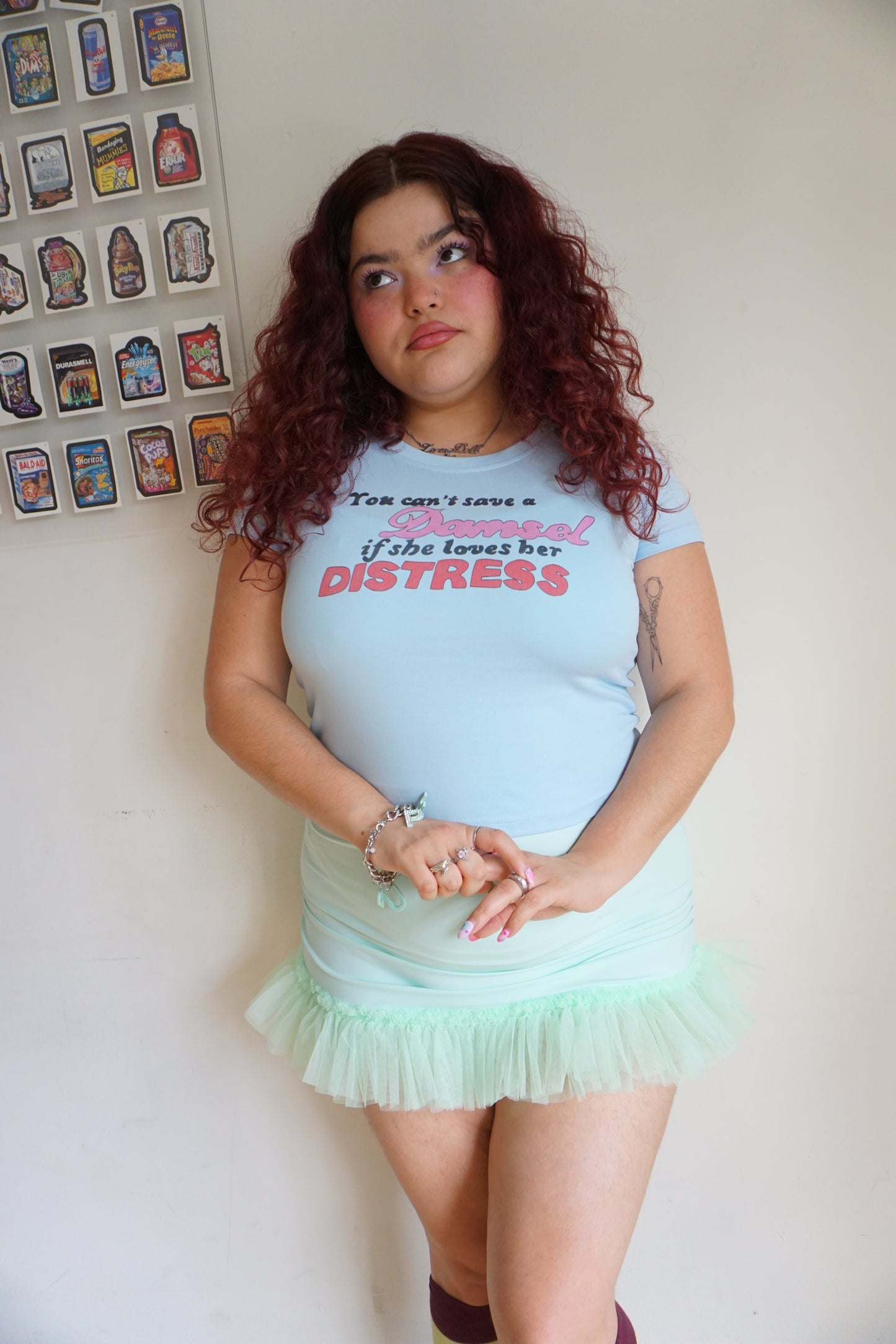 woman wearing blue baby t shirt that says you can’t save a damsel if she loves her distress