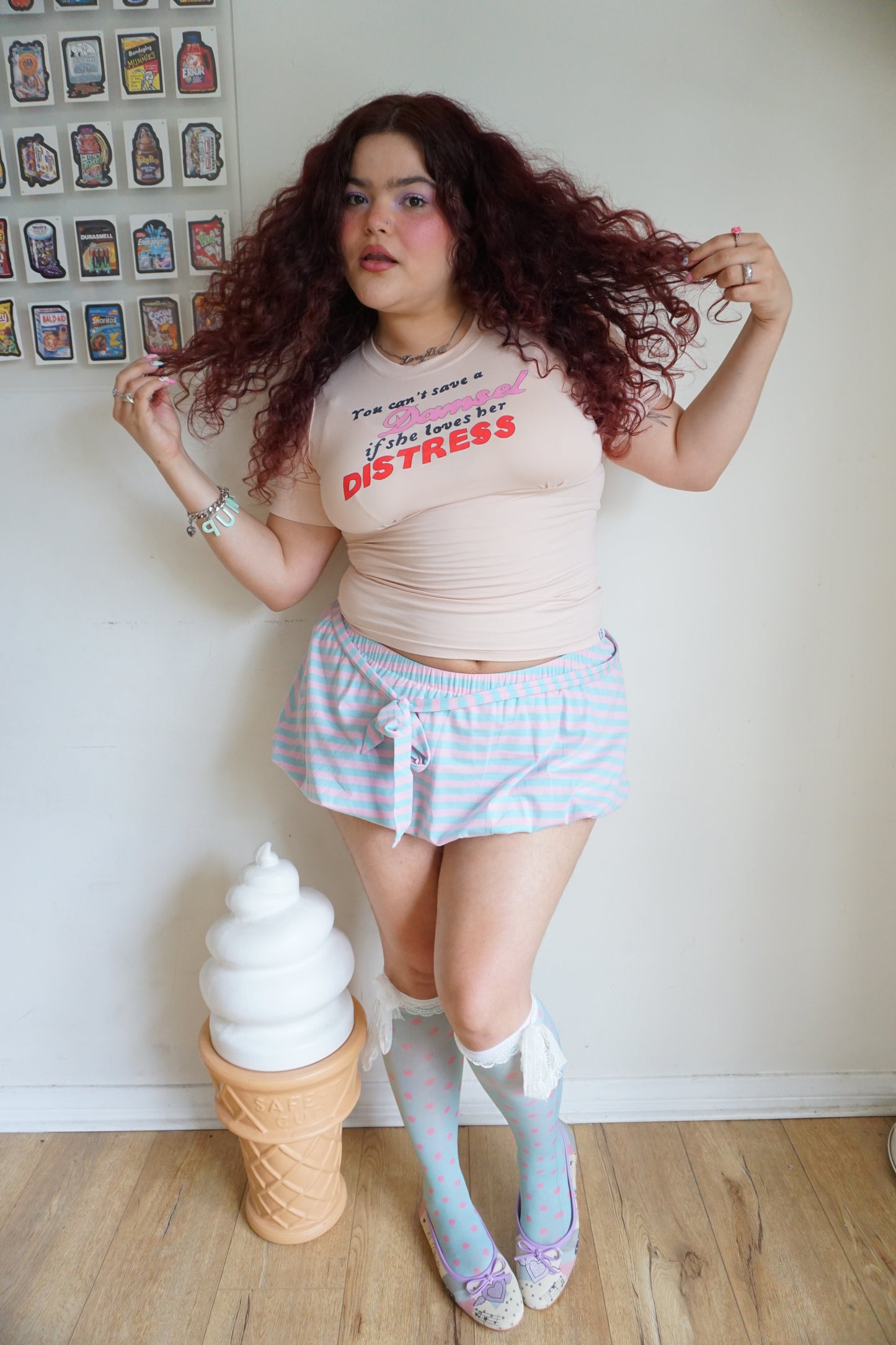 peach pink t shirt with buttons on the sleeve and a graphic that says "you can’t save a damsel if she loves her distress"