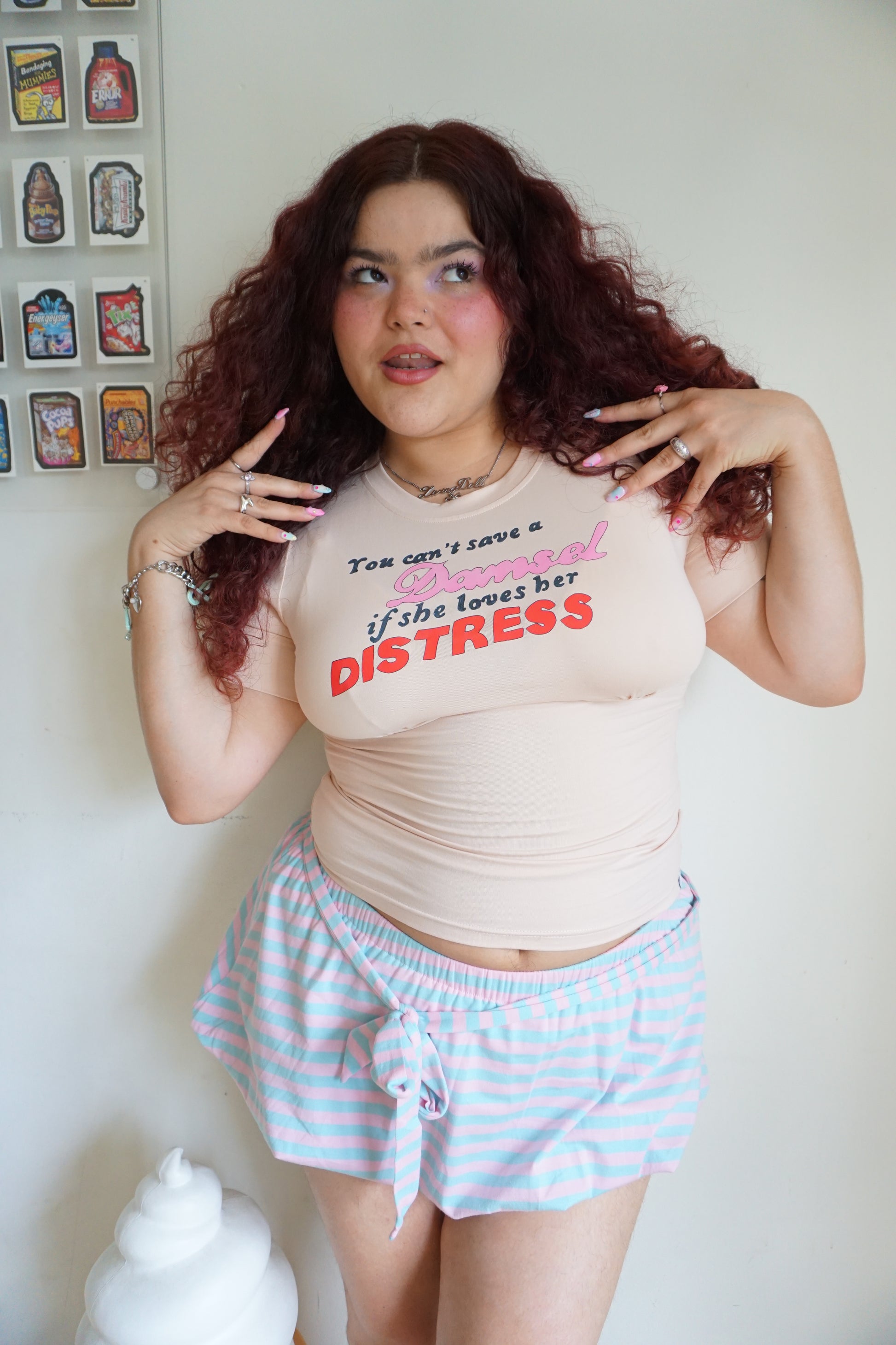 peach pink t shirt with buttons on the sleeve and a graphic that says "you can’t save a damsel if she loves her distress"