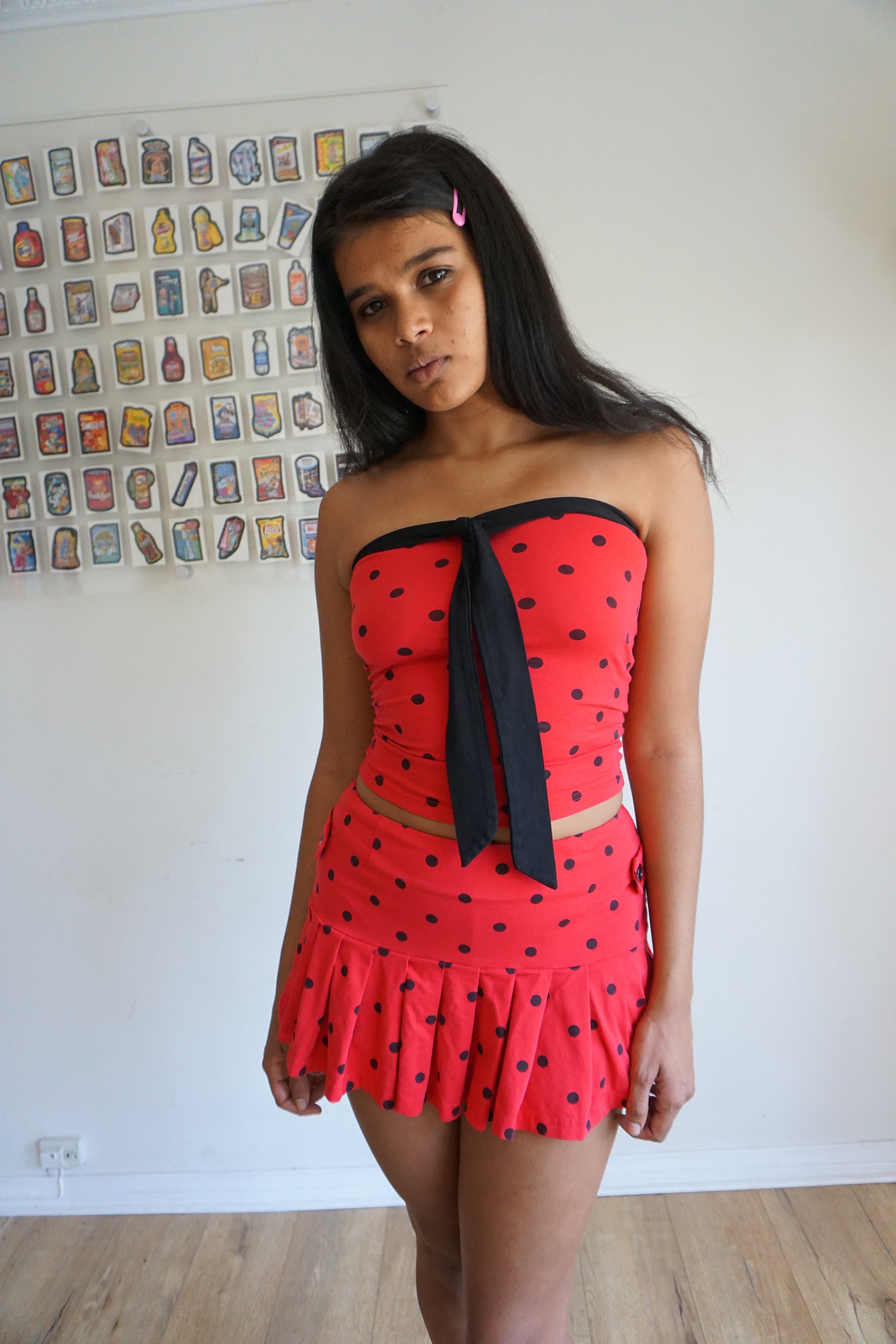 Girl wearing red tube top with black polka dots and black tie and matching skirt