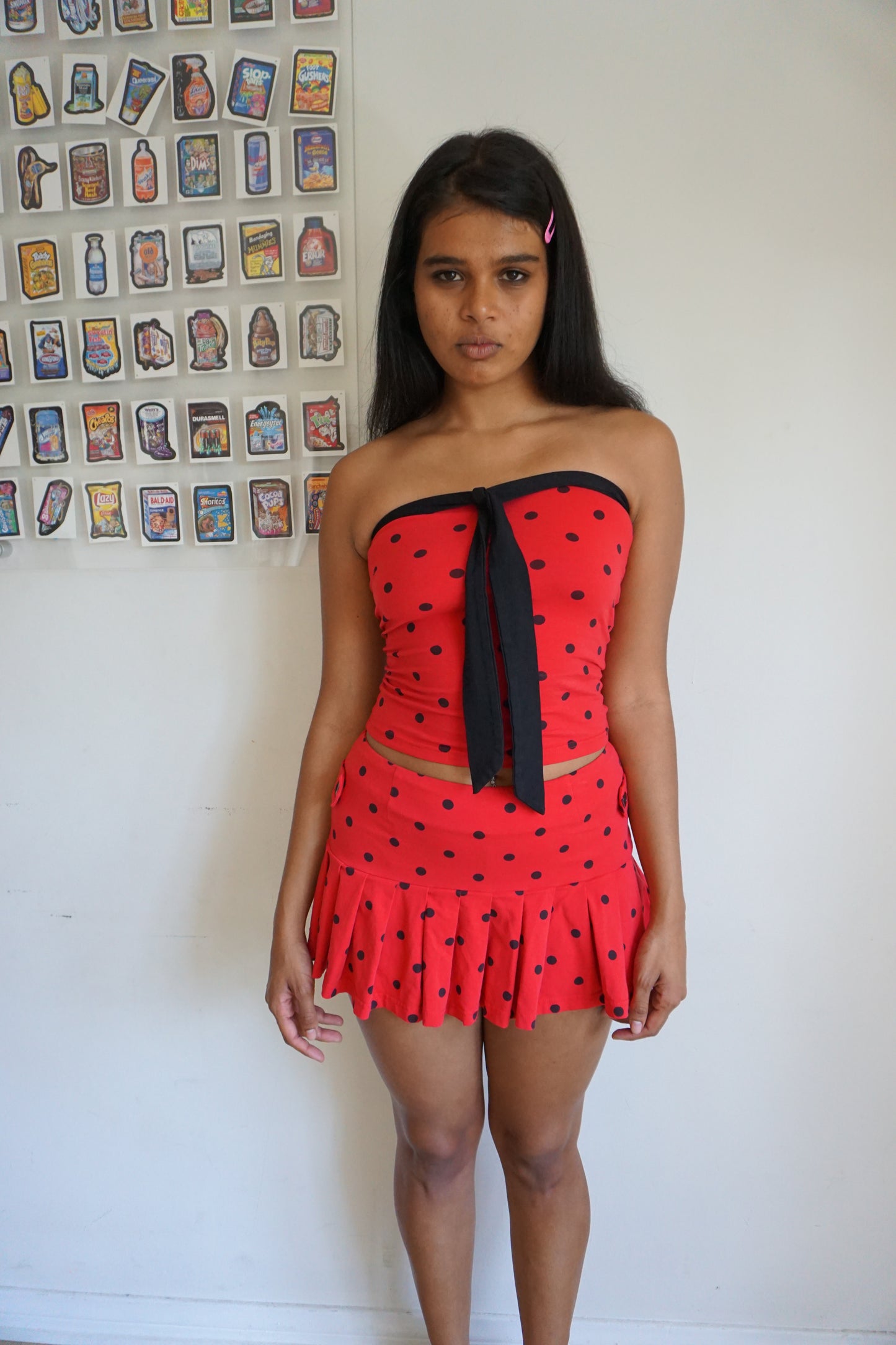 Girl wearing a red and black polka dot skirt with matching tube top 