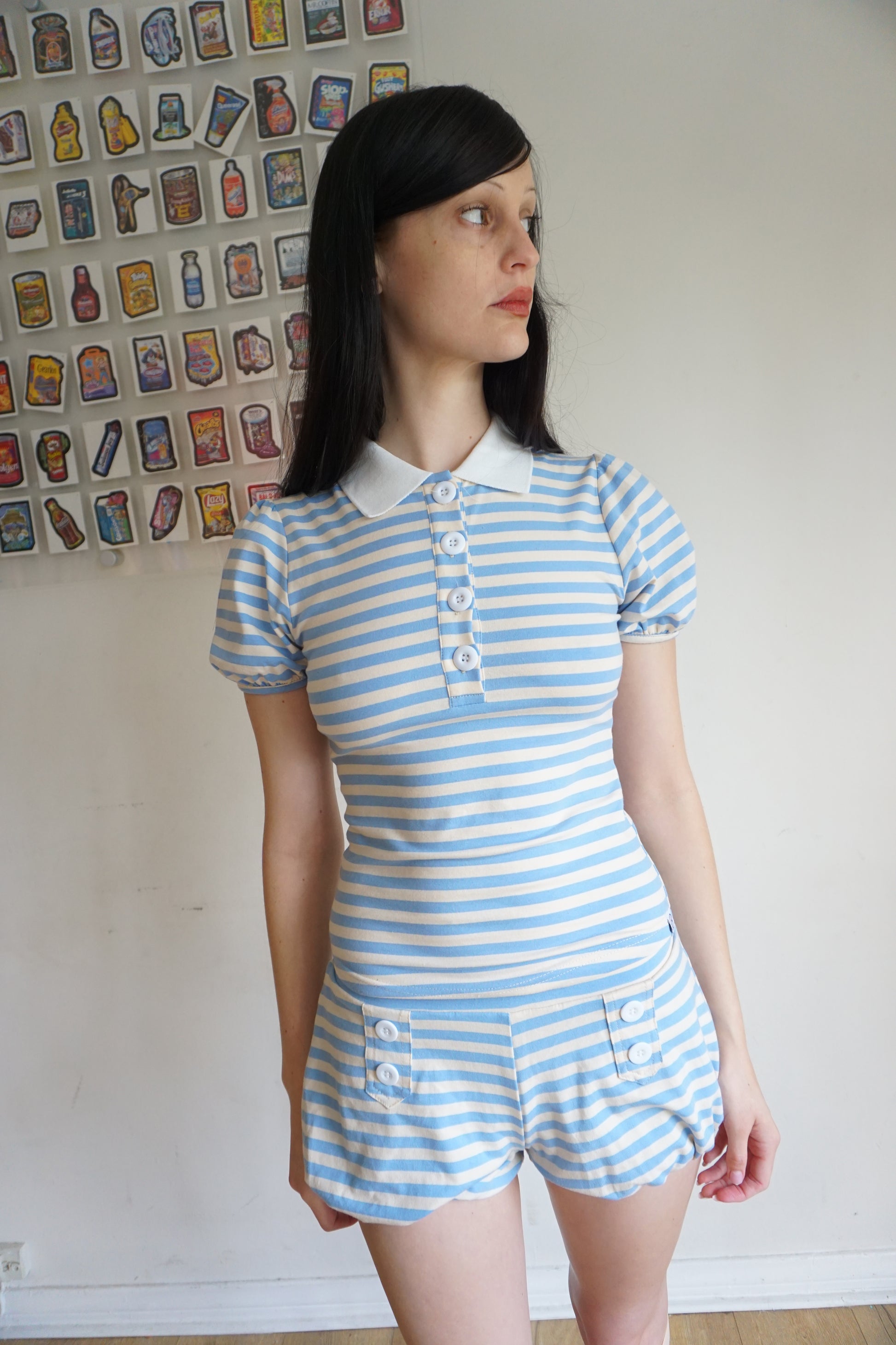 Girl with brown hair wearing a light blue/white polo and shorts set
