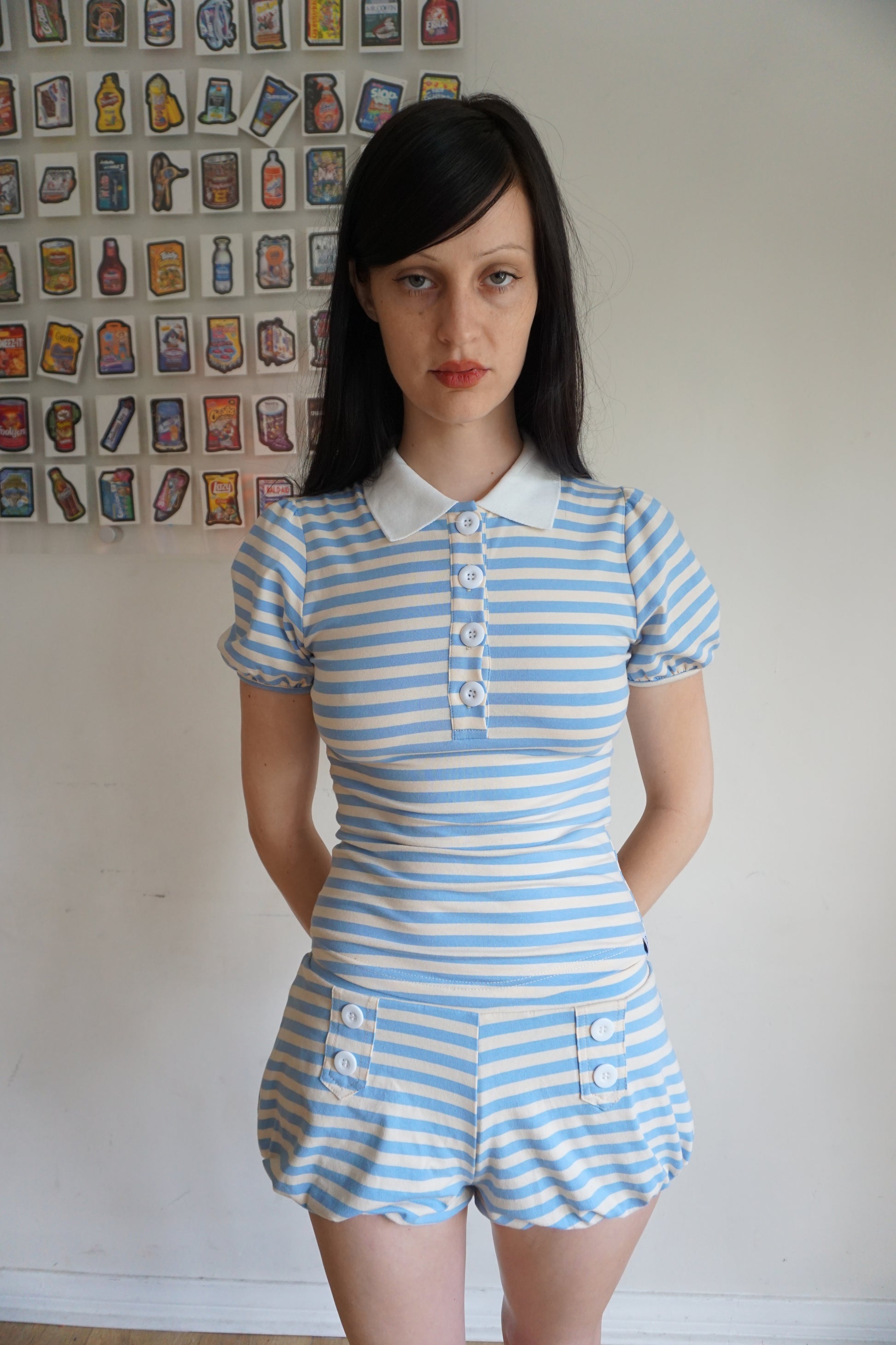 Girl with brown hair wearing a light blue and white stripe polo with matching shorts