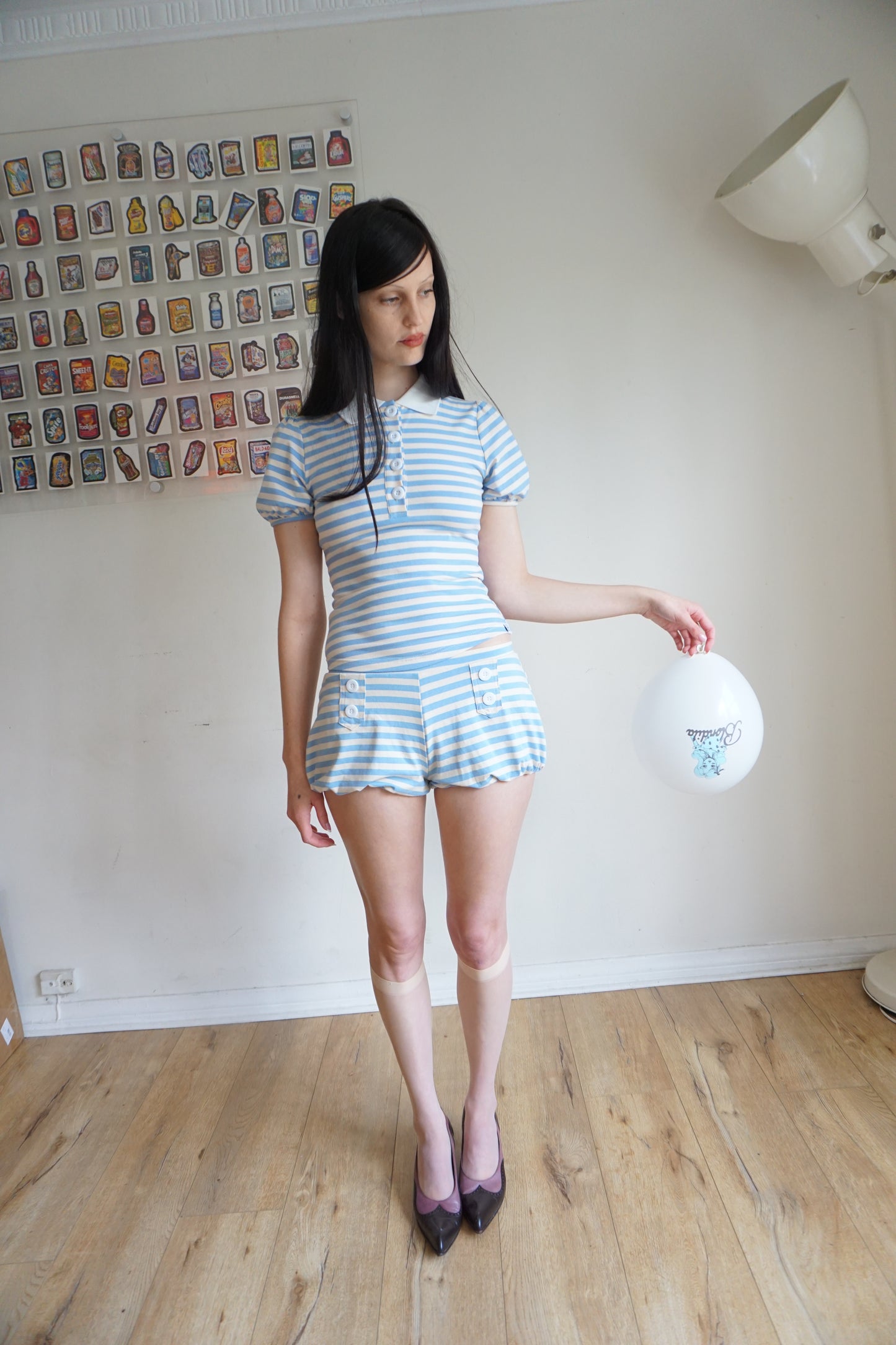 Girl wearing a blue and white polo and short set holding a baloon