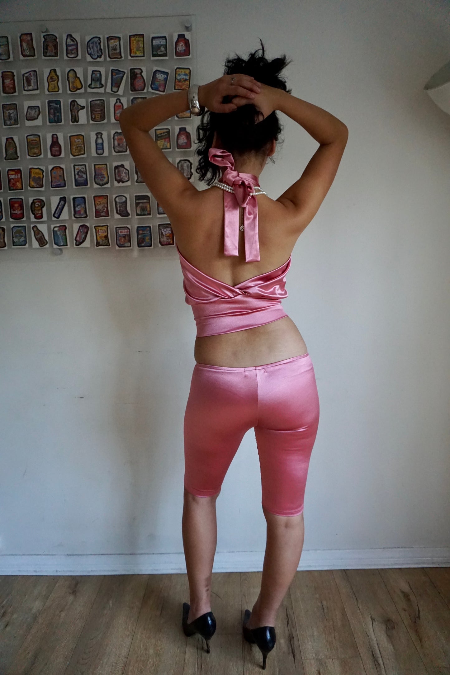 Girl wearing blush pink satin halter top with open back and matching capris