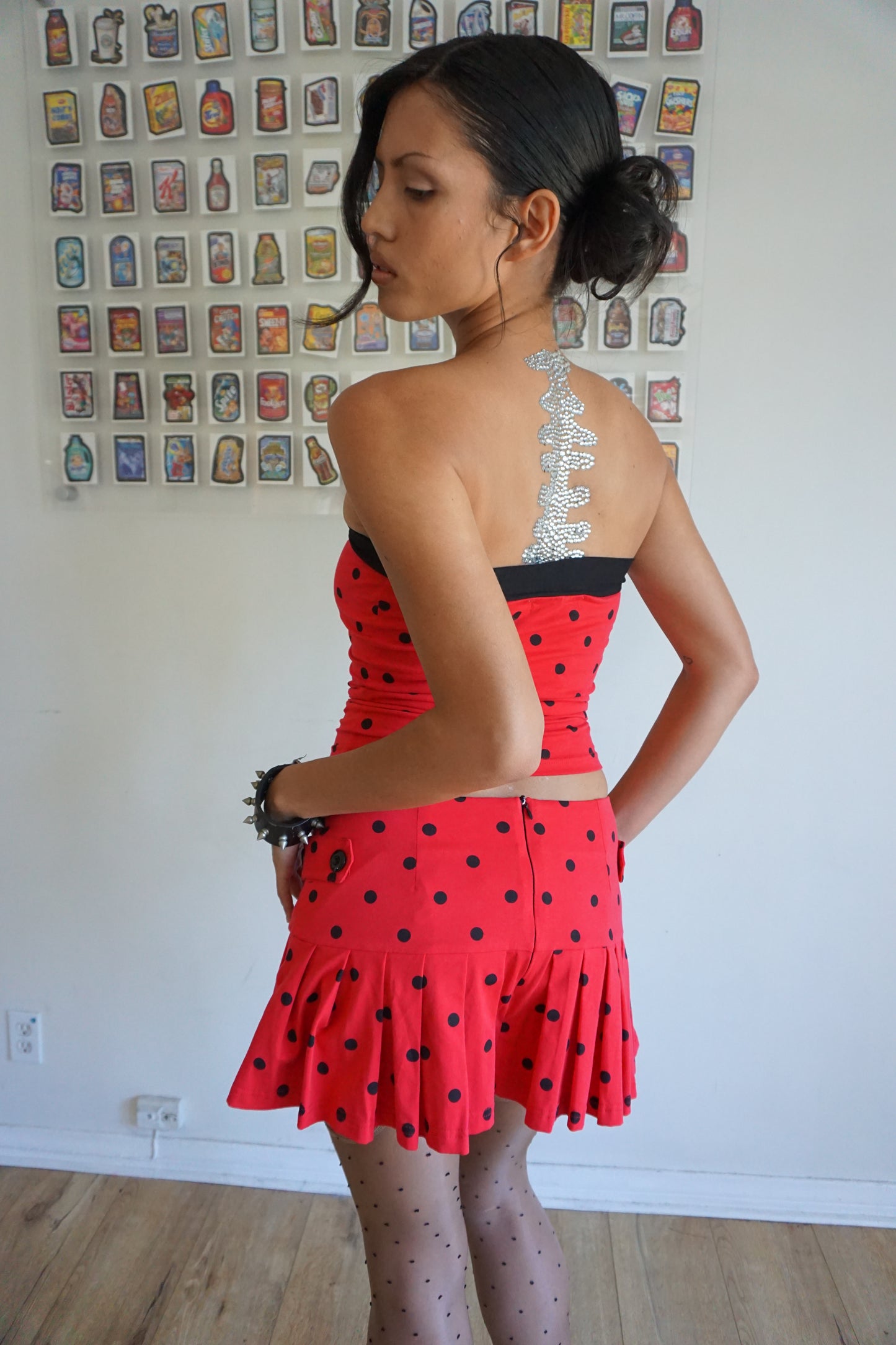 Girl wearing red tube top with black polka dots and black tie and matching skirt