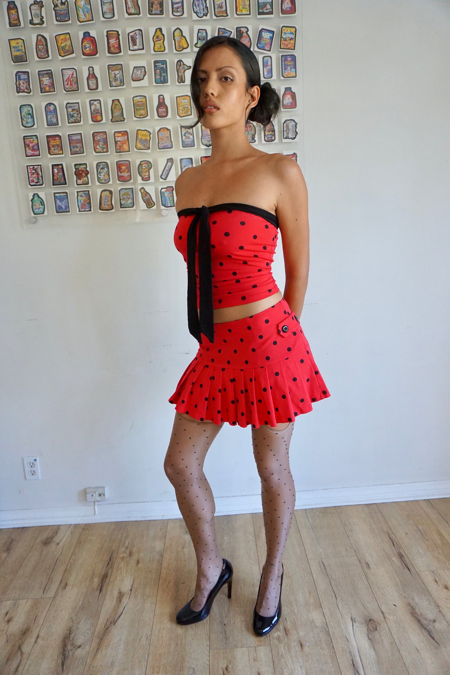 girl wearing pleated red skirt with black polka dots and buttons on the side
