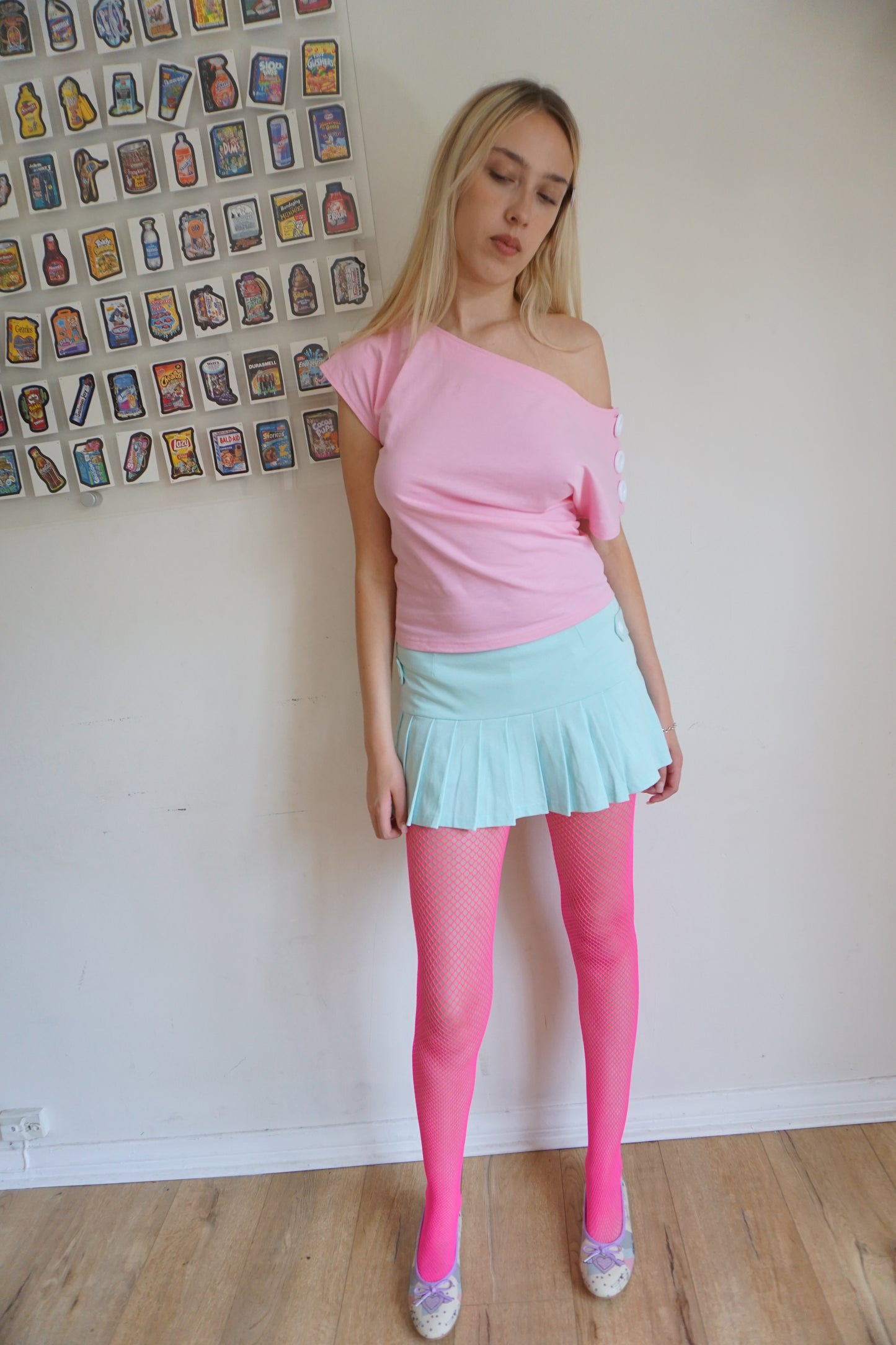 girl wearing. a pink off the shoulder top with buttons on the sleeves and pink tights