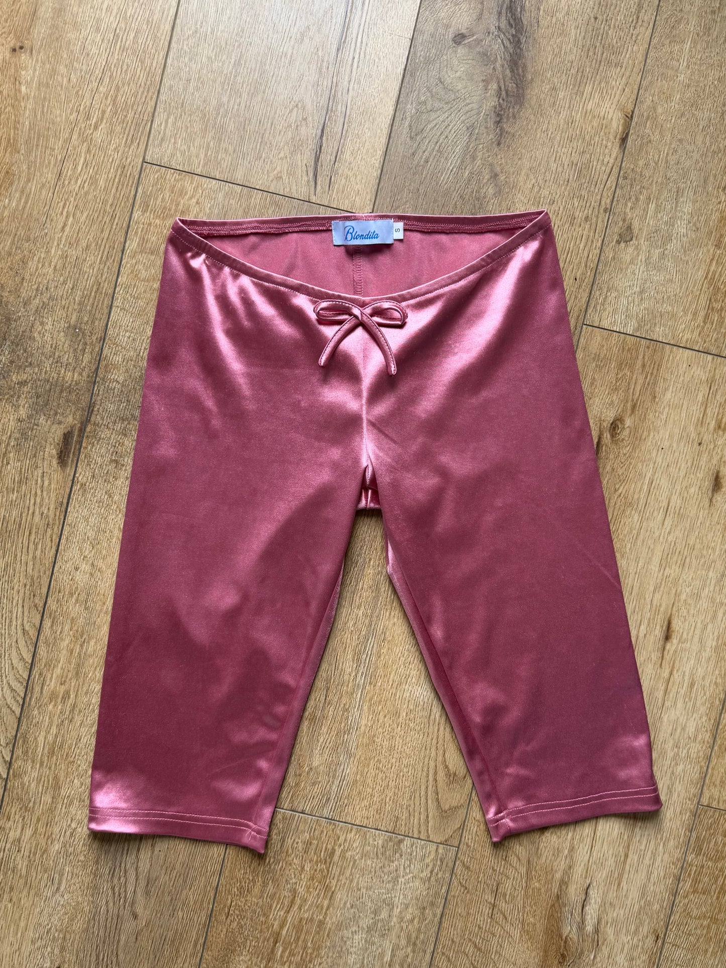 satin pink capris with a bow on a wood floor