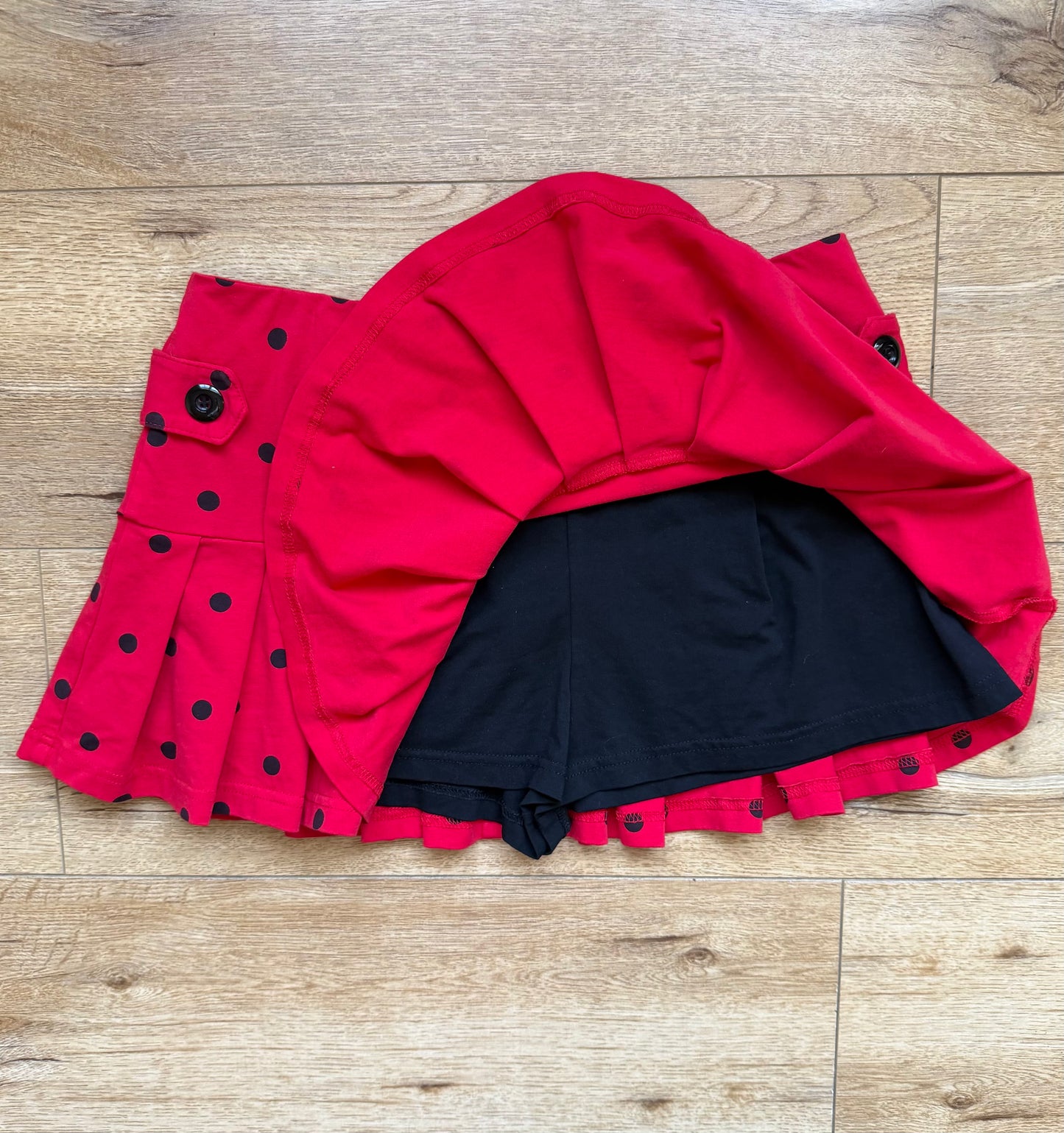 pleated red skirt with black polka dots and buttons on the side with built in shorts