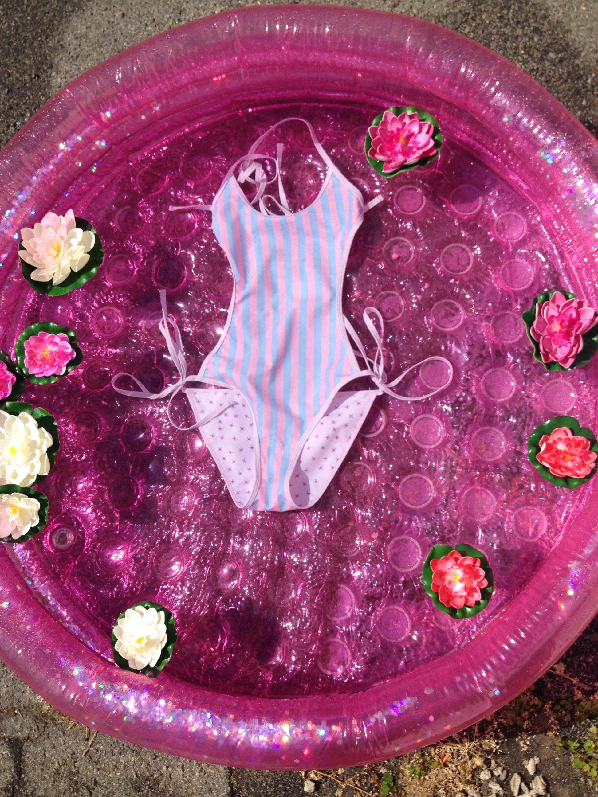 pink and blue stripe swimsuit floating in a pool with lotus flowers