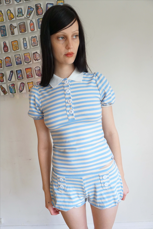 Girl with brown hair wearing a light blue and white stripe polo